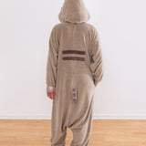 Model wearing a fleece onesie with a hood up. The back gray stripes, grey and brown striped tail, and pink paw print embroidery can be seen in this image.