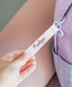 Close-up of the removable loop for the zipper handle that has the Pusheen the Cat logo on it. 