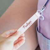 Close-up of the removable loop for the zipper handle that has the Pusheen the Cat logo on it. 