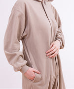 Model wearing the Pusheen Kigurumi standing at a quarter angle. The model's right hand is in the pocket present at the side of the kigurumi, and the front is blank save for the zipper starting from the base of the hood. 