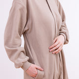Model wearing the Pusheen Kigurumi standing at a quarter angle. The model's right hand is in the pocket present at the side of the kigurumi, and the front is blank save for the zipper starting from the base of the hood. 