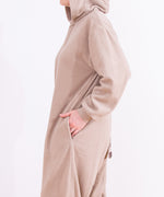 Model wearing the Pusheen Kigurumi with their side turned to the camera. The left hand is in the pocket. Fron this angle the tail detail can be seen coming off the back. 