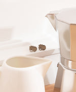Pusheen Coffee Stud Earrings show Pusheen the Cat with a steaming coffee mug. The earrings are outlined in silver.
