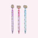 Set of three Pusheen Gel Pens. The set includes purple, pink, and blue barreled pens with all over patterns of Pusheen. Each gel pen is topped with a silicone pen topper of a gray cat. 