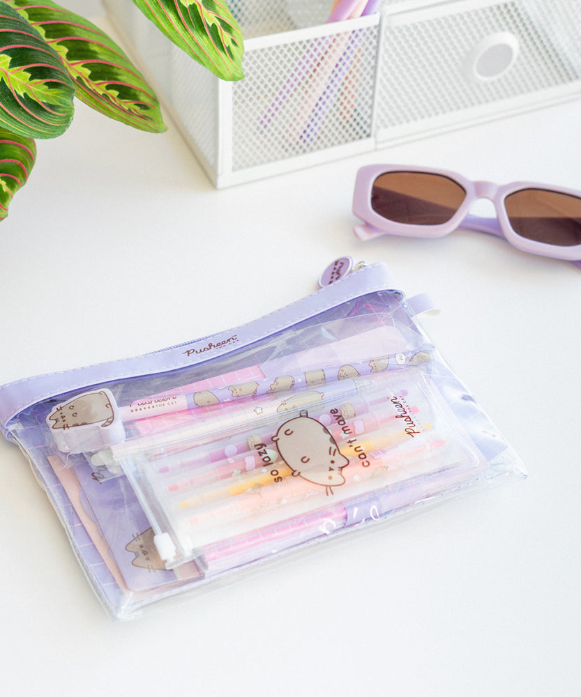 Open notebook shown held open by a Pusheen paperclip. The included pencil, eraser, and a sticker are laid on the notebook.
