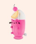 Left quarter view of the Fruit Parfait Plush. The drink-inspired plush has a whipped topping in a swirl pattern topped with a hot pink cherry with a brown stem. 