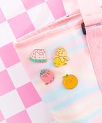 Pusheen Fruits Pin Set on a yellow background. Pusheen the Cat takes the form of a strawberry, banana, watermelon slice, and orange. The features of the pins are outlined in a shiny gold finish.