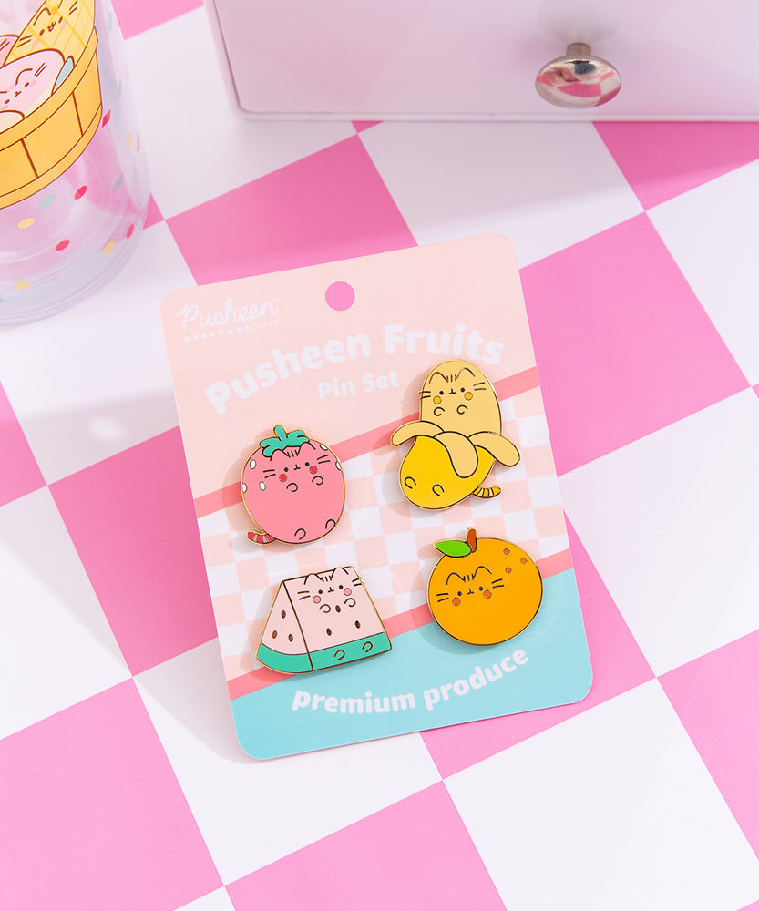 Pusheen Fruits Pin Set and backer card. The backer card has a pink checkered print, solid pink and blue backgrounds, and features the phrase "premium produce" at the bottom in white.