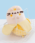 Banana Plush sits in a white wire basket. The yellow Pusheen shows Pusheen as a banana fruit with a dark yellow peel.