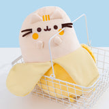 Banana Plush sits in a white wire basket. The yellow Pusheen shows Pusheen as a banana fruit with a dark yellow peel.