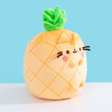 Side quarter view of the plush. The plush sits upright while Pusheen’s four paws extend off the front of the plush and do not touch the tabletop surface the plush is sitting on. 