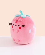 Side quarter view of the plush. The plush sits upright while Pusheen’s four paws extend off the front of the plush and do not touch the tabletop surface the plush is sitting on. 