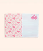 Interior view of stationery notebook. The protective first page is shades of pink and features a pattern of Pusheen as various fruits including pineapple, kiwi, cherry, and lemon. The next pages show the white with pink-lined interior writing pages.