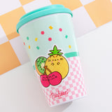 The travel mug lies on its front to show the printed back graphic. The graphic includes three Pusheen Fruits characters including a green and brown kiwi slice, a checkered yellow pineapple, and a set of red cherries on stems.  