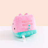 Side and back view of the Watermelon Fruit Plush. On the sides are brown circles to mimic watermelon seeds. On the back of the plush are embroidered red stripes to mimic Pusheen’s classic back stripes. Extending off the bottom back of the Pusheen is a pink and green striped tail. 
