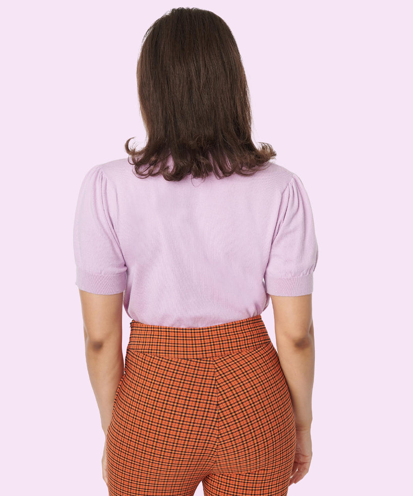 Model shows off the back of the Pusheen Halloween Knit Sweater. The lavender knit sweater does not have any embroidery graphics on the backside. The knit sweater is paired with orange and black plaid pants. 