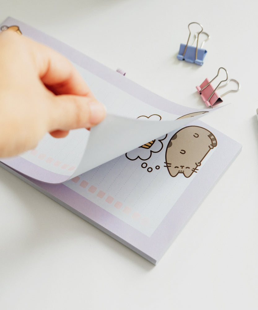 Model pulls back one page of the shopping list notepad to show the same lined page underneath.