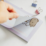 Model pulls back one page of the shopping list notepad to show the same lined page underneath.