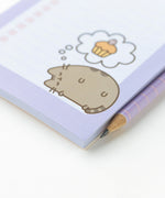 Close-up of the graphic of a sleeping cat dreaming of a cupcake printed on the bottom right hand corner of the magnetic shopping list notepad.