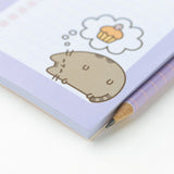 Close-up of the graphic of a sleeping cat dreaming of a cupcake printed on the bottom right hand corner of the magnetic shopping list notepad.