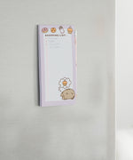 Back view of the Pusheen Magnetic Shopping List Notepad. The pink and purple cardboard backer card has two magnetic strips to ensure a strong hold. One magnet is near the top of the rectangular notepad while one magnet is near the bottom. 