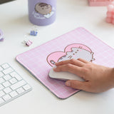 Model holds onto a computer mouse that sits on top of the Pusheen Mouse Pad.