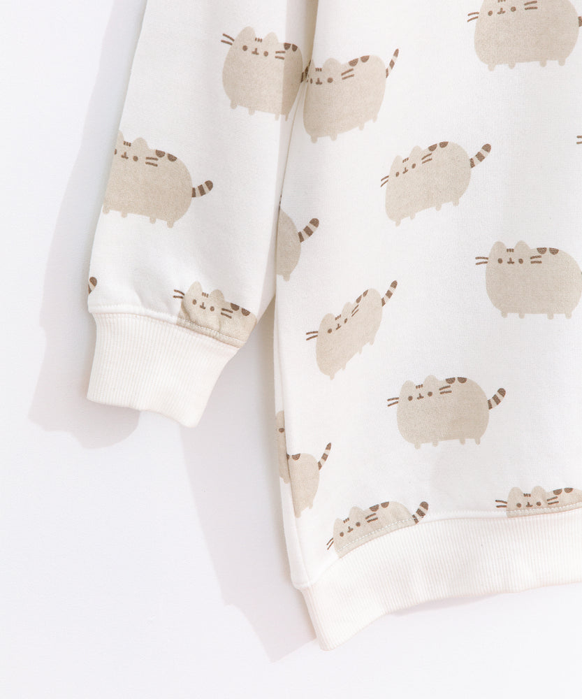 Close-up view of the Pusheen tunic top’s sleeve and hem ribbed detailing. The cream-colored top is edged with a ribbed cream finish at the collar, cuffs, and hem.  