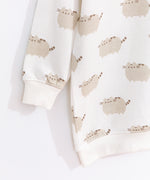 Close-up view of the Pusheen tunic top’s sleeve and hem ribbed detailing. The cream-colored top is edged with a ribbed cream finish at the collar, cuffs, and hem.  