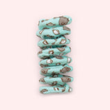 Close-up of mint green spiral cat toy that has a pattern of Pusheen the Cat holding a cup of tea surrounded by tea cups and kettles.