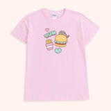A close-up view of the Snack Time Pajama Tee. The pajama shirt features a graphic of Pusheen climbing atop a juicy hamburger with a sesame seed bund. Next to Pusheen, is the phrase “YUM”, pink, and mint green hearts, and a packet of French fries.  