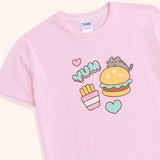 A close-up of the graphic on the front-center of the light pink, unisex pajama top. The grey and brown tabby cat is accompanied by a yellow, green, and brown hamburger, pink and mint green hearts, and yellow, pink, and white fry's packet. 