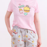 Model wearing Pusheen Snack Time Pajama Set. The pink unisex pajama top graphic matches the all over print pattern on the light grey lounge pants.