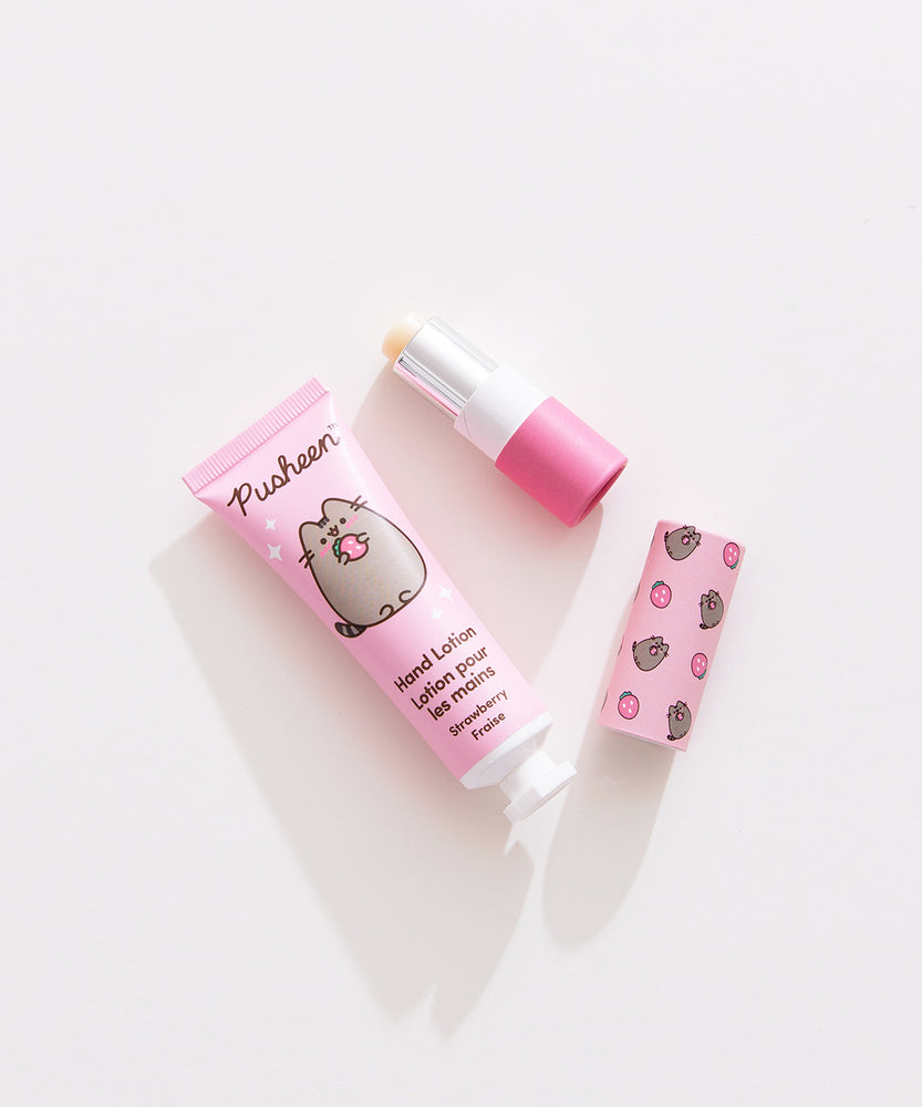 Lip balm and lotion lie on a white desktop. The Pusheen-themed set has a strawberry scented lotion. 