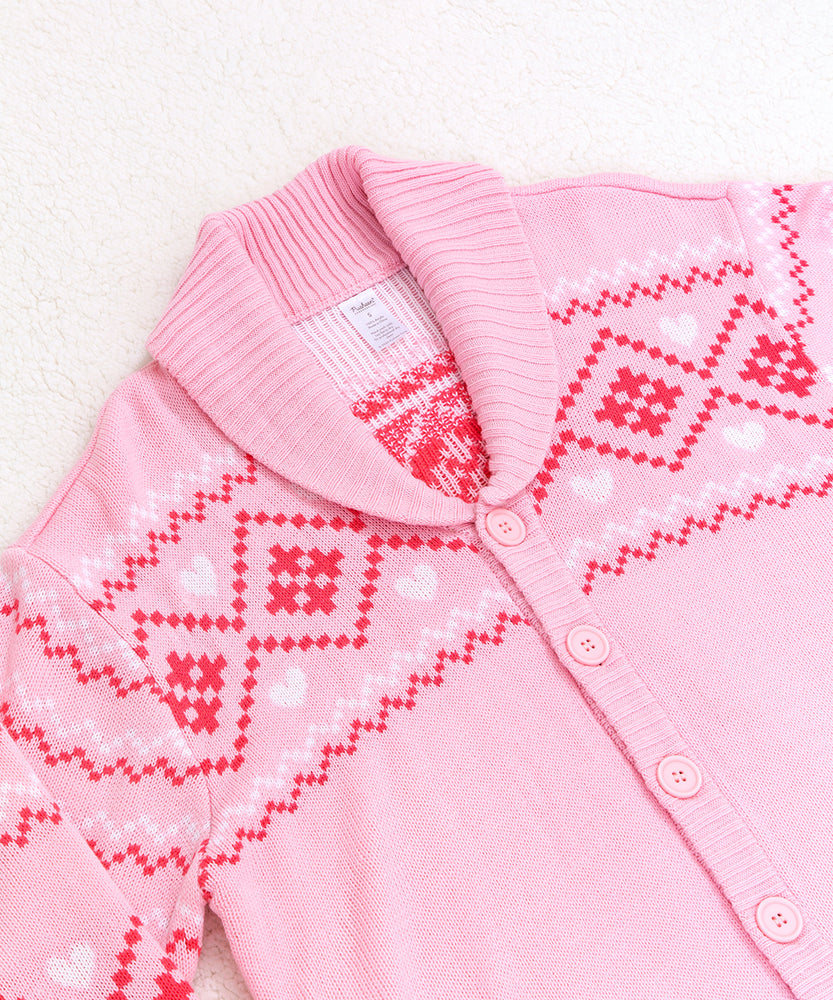 Close-up view of the diamond and heart print at the top of the cardigan. The cardigan has fold over lapels that match the ribbed hem and cuffs. The pattern features a variety of diamonds, hearts, and squiggles.  