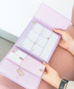 Model holds open the pink and purple Pusheen binder to show size and scale of the weekly agenda binder. 