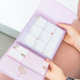 Model holds open the pink and purple Pusheen binder to show size and scale of the weekly agenda binder. 