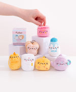 Model holds the top portion of the pot kitchen keychain. The pink plush features Pusheen the Cat taking the form of a cooking pot. The plush has Pusheen's face embroidered on the front of the plush. 