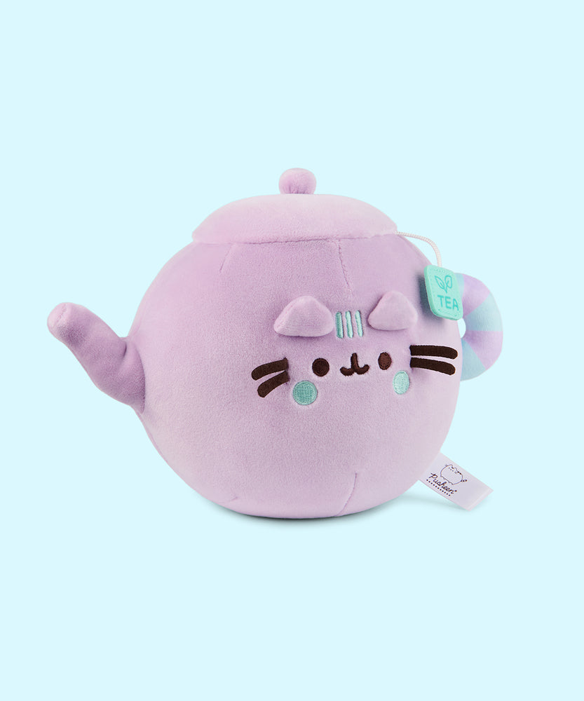 Side quarter view of the Teapot plush. Pusheen's spot lid and body color are all lilac while her tail mimic the handle of the tea pot. The handle is striped lilac and light mint green.