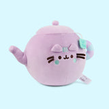 Side quarter view of the Teapot plush. Pusheen's spot lid and body color are all lilac while her tail mimic the handle of the tea pot. The handle is striped lilac and light mint green.