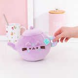 Model holds handle of the Teapot Plush. The handle is a striped light blue and lilac purple ring.
