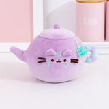 Pusheen's Kitchen Teapot Squisheen Plush sitting on a white surface. Pusheen the Cat takes the form of a lilac tea kettle. One paw extends to become the spout.