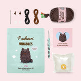 Contents included in the Intermediate Pip Crochet Kit. The kit includes a needle, two plastic eyes, two clear buttons, all necessary yarn colors, a custom mint green crochet hook, stuffing, and a how-to guide. 