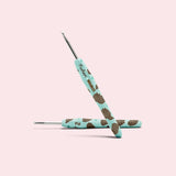 Close-up of the custom crochet hook. The mint green handle features an all over print of Pusheen's brother Pip and the Pusheen x The Woobles collaboration logo.