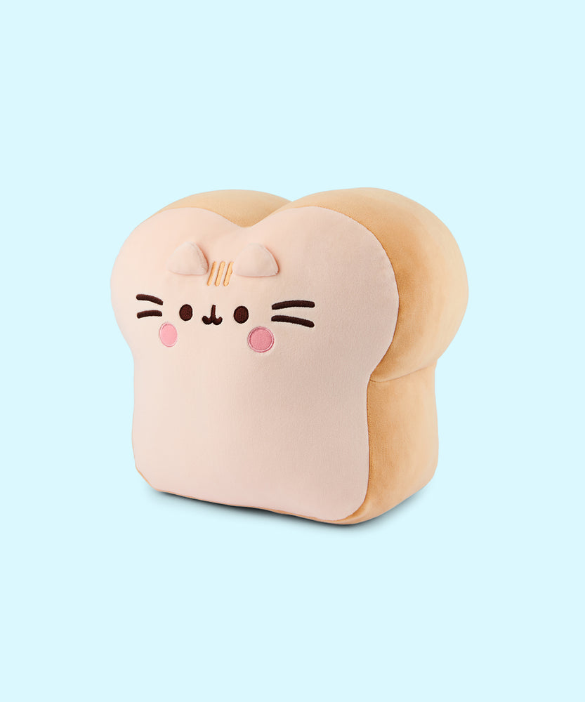 Side quarter view of the Pusheen White Bread Squisheen. Pusheen's eyes, mouth, and whiskers are embroidered in dark brown. Pusheen has a light pink color blush circles under her eyes. Between the two triangular 3D ears are Pusheen's classic 3-stripes in a light cream thread color.