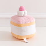 Back view of the Strawberry Sponge Cake plush. The cake plush has light pink icing, light yellow cake layers, and white cream extending around the back of the plush.