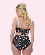 Model shows off the back of the swimsuit. The top features a corset-style tie back while the bottoms have a high-waisted retro-fit.