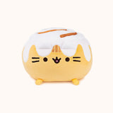 Front view of the Cinnamon Roll Squisheen in front of a white background. Pusheen's frosting covered ears blends in visually with the rest of the frosting on top of her.