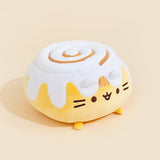 A quarter profile view of the Cinnamon Roll Squisheen, facing the right, in front of a cream background. The frosting on top of the cinnamon bun has an extra bit of plush filling.