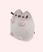Left quarter view of Pusheen plush. This view shows Pusheen’s four paws extending off her body and to showcase all four bottom of the paws. The plush tail extends slightly off the back of the plush and is peeking out in this angle.