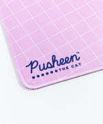 Close up of the Pusheen the Cat Logo on the lower left side of the Gaming Desk Mat. The edges of the mat are sewn, and the rubber base is partially visible.